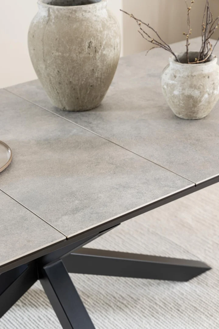 Een close-up van de Eettafel Hemel 100 x 76 CM Rechthoek in steenlook keramiek staal, gestileerd met twee rustieke keramieken vazen met gedroogde takken, op een licht getextureerd vloerkleed.