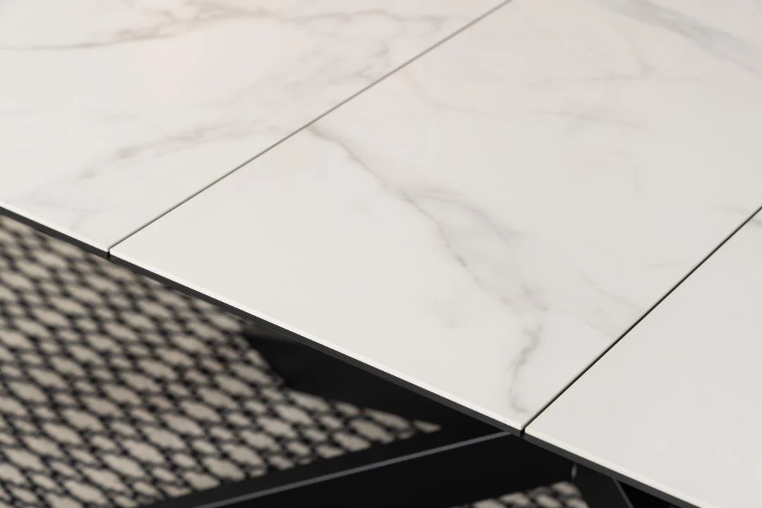 Een close-up van de Eettafel Irwine 240 x 100 CM Rechthoek in wit keramiek met subtiele grijze adering, getoond boven een zwart-wit gedessineerd vloerkleed.