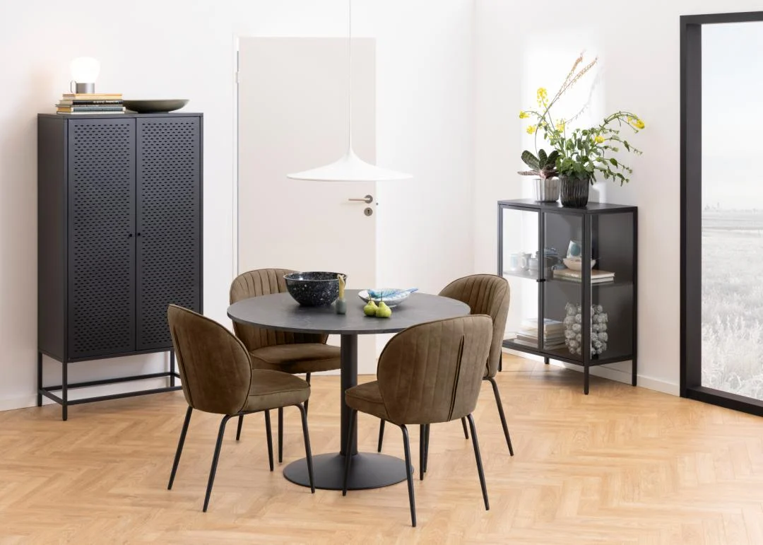 Een moderne eethoek met de Eettafel Nieuwe Sfeer 110 CM Rond MDF Staal, vier bruine gestoffeerde stoelen, een zwarte metalen kast, een glazen dressoir met planten en decor en een hanglamp op een lichthouten visgraatvloer.