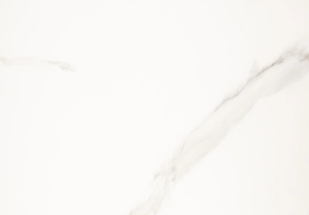 De Salontafel Zwart, Wit 70 CM Rond heeft een helder wit kunststof oppervlak met zachte grijze adering in een diagonaal patroon, wat zorgt voor een strakke, minimalistische en elegante uitstraling.