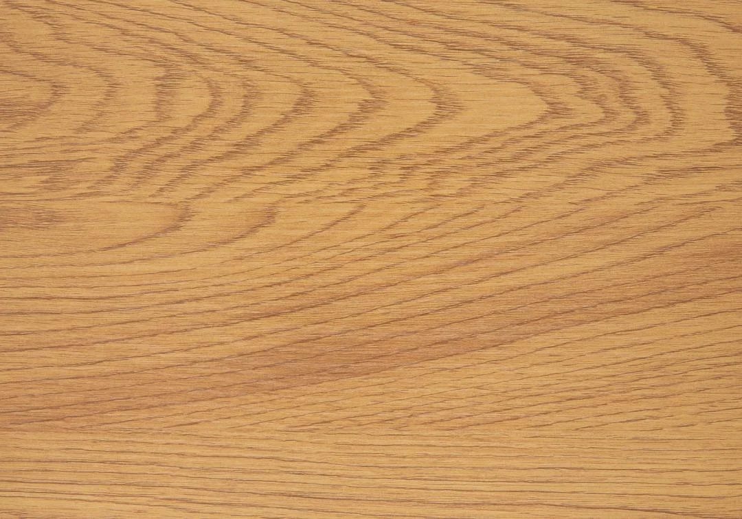 De Eettafel Wilma 80 x 75 CM Rond Mdf Staal heeft een lichtbruin houten oppervlak met zichtbare natuurlijke nerfpatronen en subtiele lijnen, aangevuld met een mat zwart onderstel voor een warme, gestructureerde en moderne uitstraling.