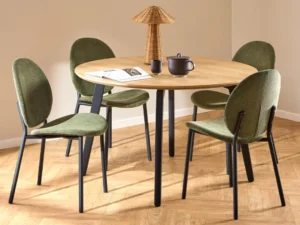 De Eettafel 1 120 CM Rond Eikenhout met matzwarte stalen poten is gecombineerd met vier groen gestoffeerde stoelen met zwart onderstel, gestyled in een lichte moderne kamer met lichte vloer- en tafeldecoratie.