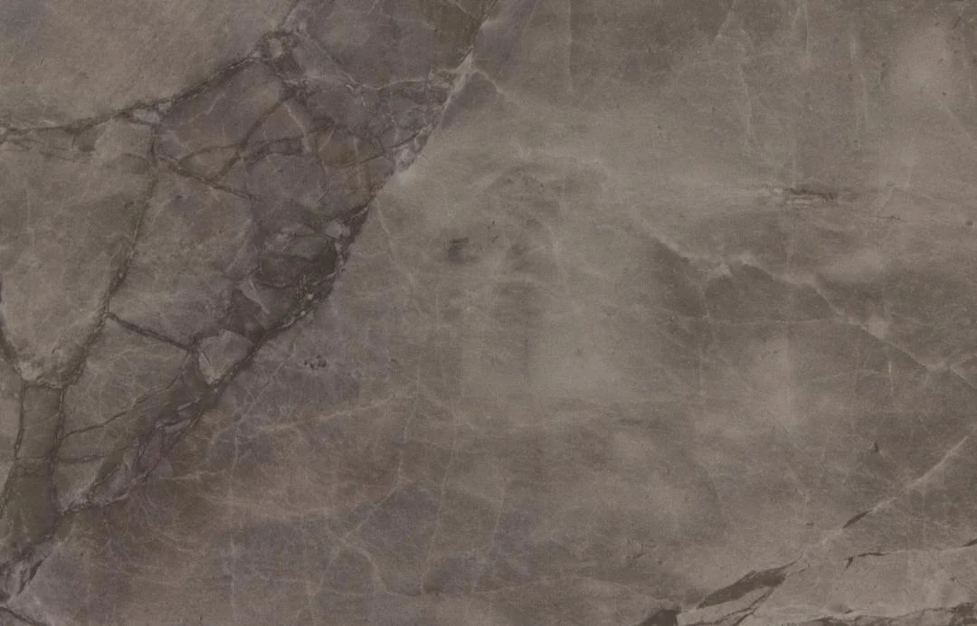 Een close-up van de Eettafel Nieuwe Sfeer 80 x 75 CM Rond toont een keramiek uitschuifbaar tafelblad met tinten grijs, bruin en subtiele paarse aderen, waardoor een natuurlijk gemarmerd patroon ontstaat.