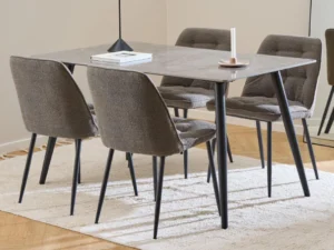 De Eettafel Wicklow 80 x 75 CM Rond Keramiek, met een grijs marmeren blad, is gekoppeld aan vier gecapitonneerde grijze stoelen op een crèmekleurig vloerkleed. Op de tafel staan een gesloten boek en een kandelaar, in een kamer met een spiegel en houten vloer.