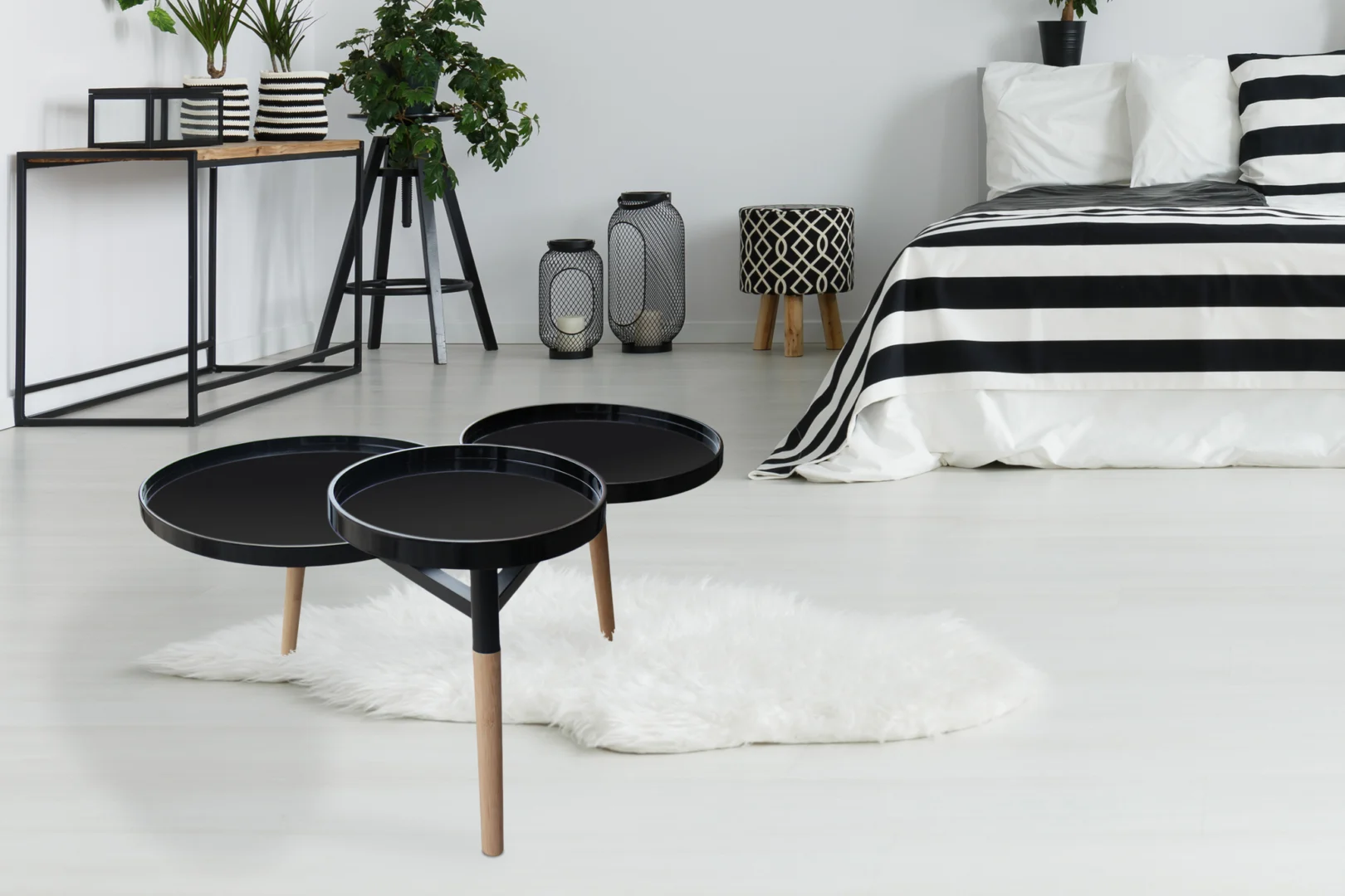 Moderne slaapkamer met de Bijzettafel Zwart 30 CM Rond Bamboe bijzettafels met houten poten op een wit vloerkleed, een zwart-wit gestreepte sprei en minimalistische accenten zoals planten en lantaarns.