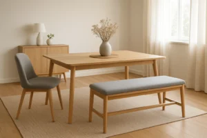 Een minimalistische eetkamer met een houten tafel, een grijze stoel met kussens en een bijpassende bank op een beige vloerkleed. Net als "wat is het verschil tussen een salontafel en een bijzettafel", dient elk stuk zowel functie als stijl te midden van zacht natuurlijk licht.