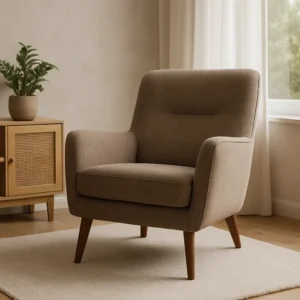 Een moderne beige fauteuil met houten poten staat op een licht vloerkleed in een gezellige kamer, naast een houten kast met een potplant en een raam met witte gordijnen - perfect om je af te vragen wat het verschil is tussen een salontafel en een bijzettafel.