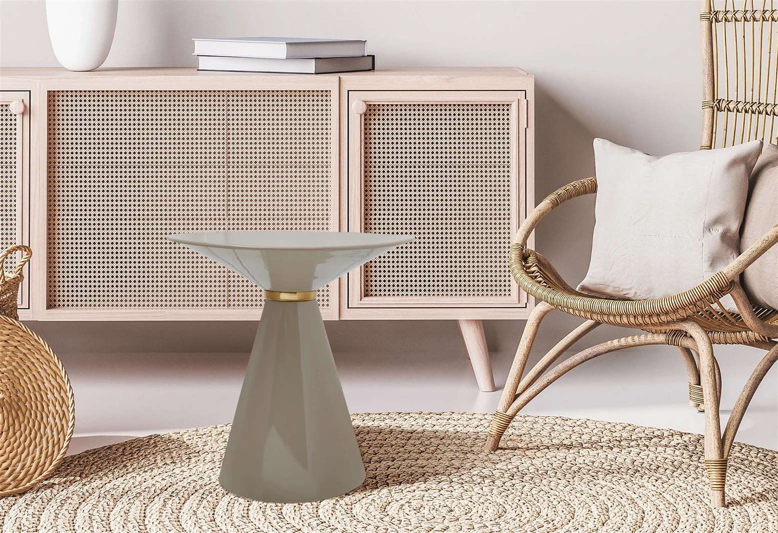 Een moderne woonkamer met een licht houten kast, een rotan stoel met een beige kussen, een rond geweven vloerkleed, een mand en de Bijzettafel Taupe Rond Ijzer - een klein rond ijzeren bijzettafeltje in taupe.