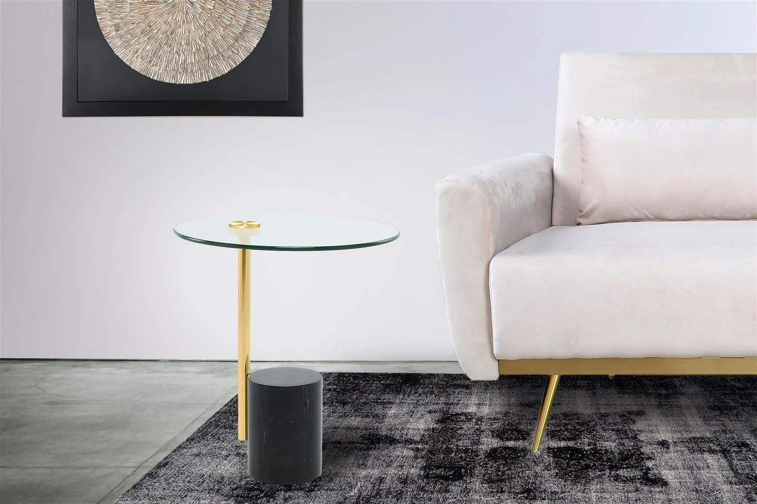 Een moderne woonkamer met een lichtgekleurde bank, een vloerkleed met donker patroon, abstracte muurkunst met een cirkelvormig ontwerp en de Bijzettafel Zwart, Goud 17 CM Rond Marmer-een ronde marmeren bijzettafel met zwarte en gouden poten.