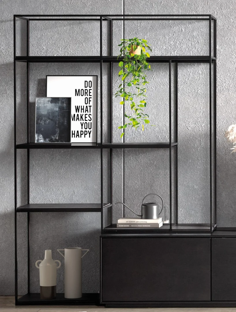 De Izola BOEKENREK DO, een strakke zwarte metalen plank, staat tegen een grijze muur met ingelijste kunst (op een ervan staat "DO MORE OF WHAT MAKES YOU HAPPY"), een hangende plant, gieter en decoratieve vazen.