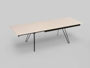 De Izola TAFEL 180-280 WWM is een minimalistische rechthoekige tafel met een licht houten blad dat is opgedeeld in twee delen, waarvan één uiteinde iets omhoog staat en wordt ondersteund door zwarte metalen poten. De tafel staat tegen een effen grijze achtergrond.