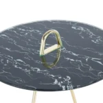De Bijzettafel Zwart, Goud Staal heeft een rond blad met zwart marmerpatroon, goudkleurige metalen poten en een opvallende gouden driehoekige handgreep in het midden van het tafelblad.