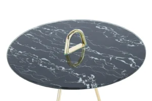 De Bijzettafel Zwart, Goud Staal heeft een rond blad met zwart marmerpatroon, goudkleurige metalen poten en een opvallende gouden driehoekige handgreep in het midden van het tafelblad.
