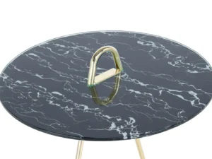 De Bijzettafel Zwart, Goud Staal heeft een rond blad met zwart marmerpatroon, goudkleurige metalen poten en een opvallende gouden driehoekige handgreep in het midden van het tafelblad.