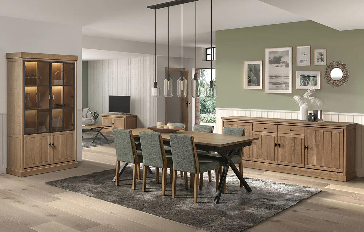 Eetkamer in lichte kleuren met houten JURA VITRINE en dressoir. Zes stoelen rondom een tafel met grijze vloerkleed. Moderne hanglampen boven de tafel.