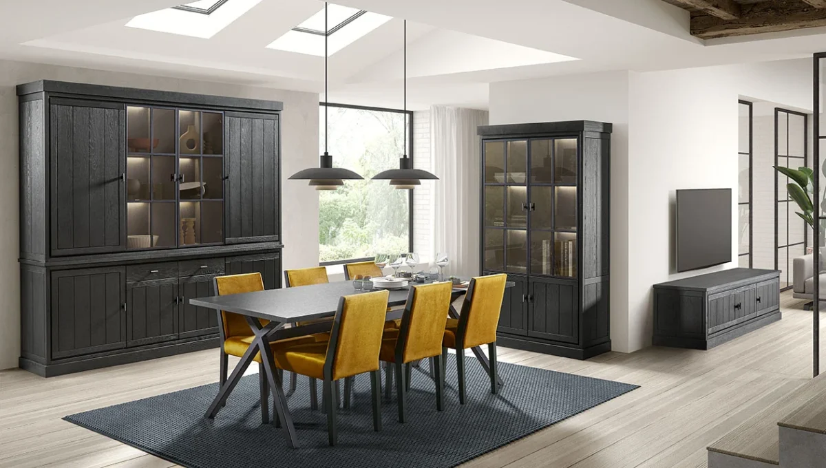 Interieur met Jura vitrinekast EL99 in donker hout. Eetkamer met gele stoelen en blauw tapijt. Zonnig licht door dakramen en grote ramen.