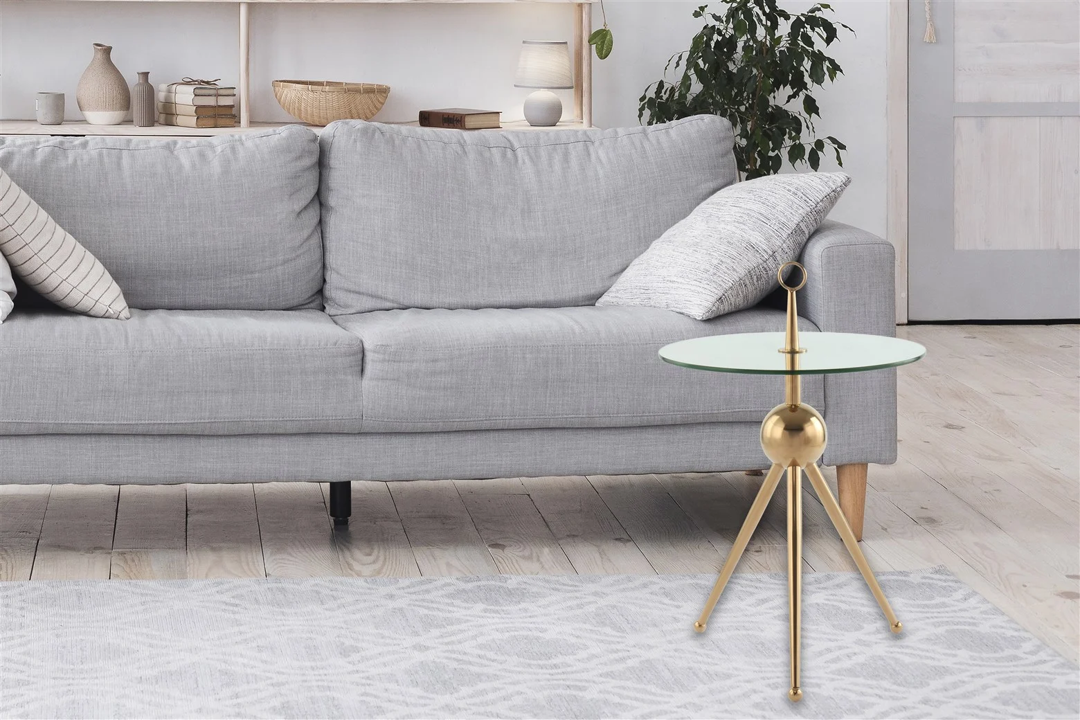 Een moderne woonkamer met een lichtgrijze bank, witte en grijze kussens, een vloerkleed met patroon, de Bijzettafel Staal Compact als stijlvolle ronde bijzettafel, een plant in pot en witte planken met decor op de achtergrond.