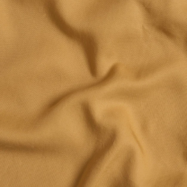 Close-up van Dekbedovertrek 120x150 Geel voor elk seizoen, met zachte mosterdgele stof met zachte plooien en een knusse textuur.