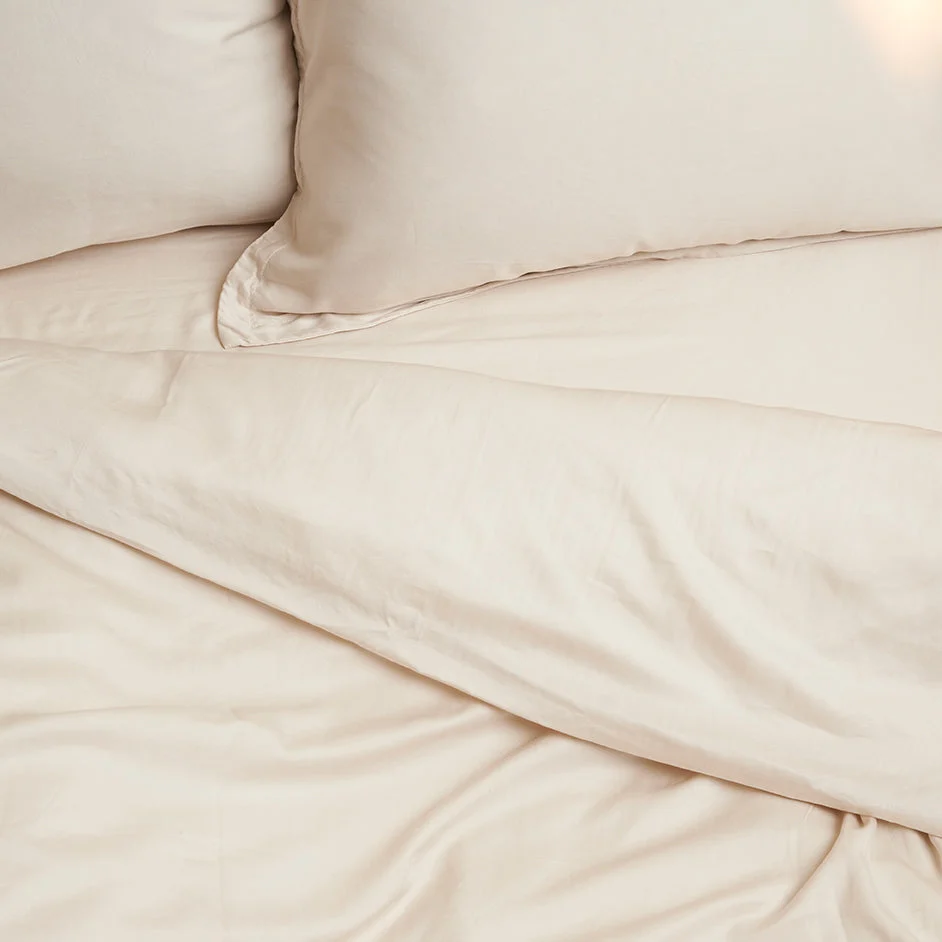 Beige TENCEL hoeslaken detail. Zachte, ademende stof met subtiele glans. Close-up, natuurlijk licht, warme tinten.