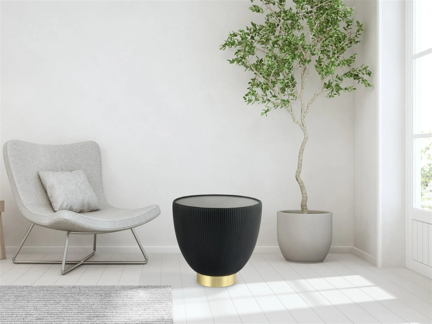 In een moderne, minimale woonkamer staan een grijze fauteuil, een hoge boom in potten en de Bijzettafel Zwart Steen Design - een zwart met gouden ronde accenttafel - op een witte houten vloer tegen een lichtgekleurde muur.