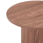 Close-up van de bovenkant en zijkant van de Nora Bijzettafel - Ø40cm Walnoot, met de gladde afwerking en zichtbare houtnerfpatronen.