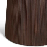 Een close-up van het onderste deel van de Mokka Ronde Eettafel Donkerbruin (Ø150cm), met de donkerbruine, verticaal geribbelde cilindrische basis tegen een witte achtergrond.