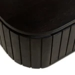 Close-up van de rand van het Nachtkastje, met de gladde bovenkant en de gestructureerde, gegroefde zijkanten in donkerbruin industrieel mangohout.