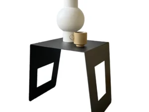 De Brug - Bijzettafel - Zwart is een moderne zwarte bijzettafel met rechthoekige uitsparingen aan elke kant, afgebeeld met een ronde witte vaas en een klein beige kopje tegen een witte achtergrond.