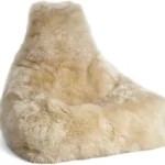 De Zitzak Premium Lang Wol is een grote, beige zitzak met zacht, ruig imitatiebont en een ondersteunende rugleuning, die een relaxte en uitnodigende zit biedt.