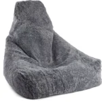 De Zitzak Schapenvacht Kort Wol Grijs Kort is een grote, grijze zitzakstoel gemaakt van korte wollen schapenvacht, met een hoge rugleuning, zachte pluche textuur en een uitnodigende, ontspannen vorm.