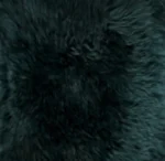 Een close-up van de Zitzak Schapenvacht Lang Wol Groen toont een dichte, zwarte en pluizige vacht met een zachte, licht golvende textuur en diepgroene accenten.