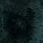 Een close-up van de Zitzak Schapenvacht Lang Wol Groen toont een dichte, zwarte en pluizige vacht met een zachte, licht golvende textuur en diepgroene accenten.
