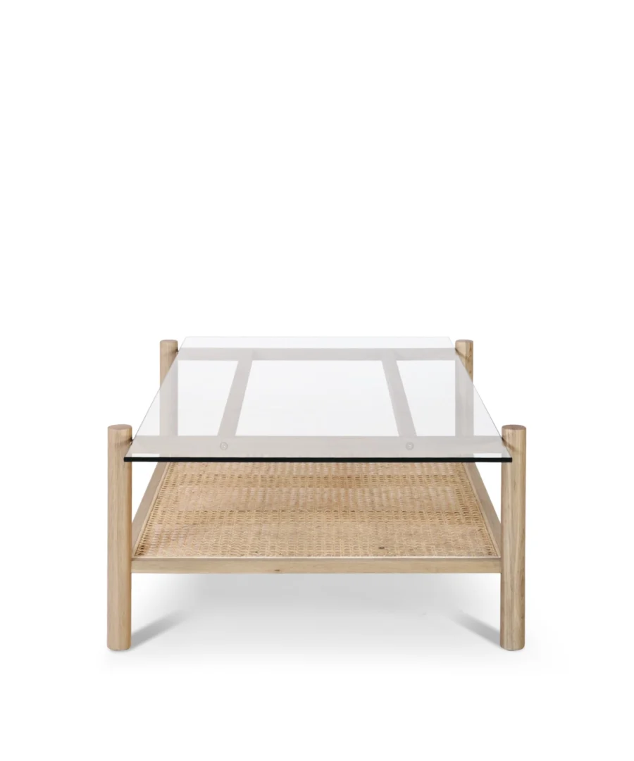 De Salontafel 69 x 37 CM is een moderne salontafel met een blad van helder glas, een frame van licht hout en een plank van gevlochten rotan eronder, tegen een effen witte achtergrond.