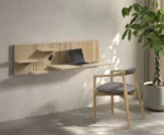 Lichte houten Napoli bureau E02M aan de muur met laptop, kleine plankjes en een bureaustoel. Zachte belichting, minimalistisch design.