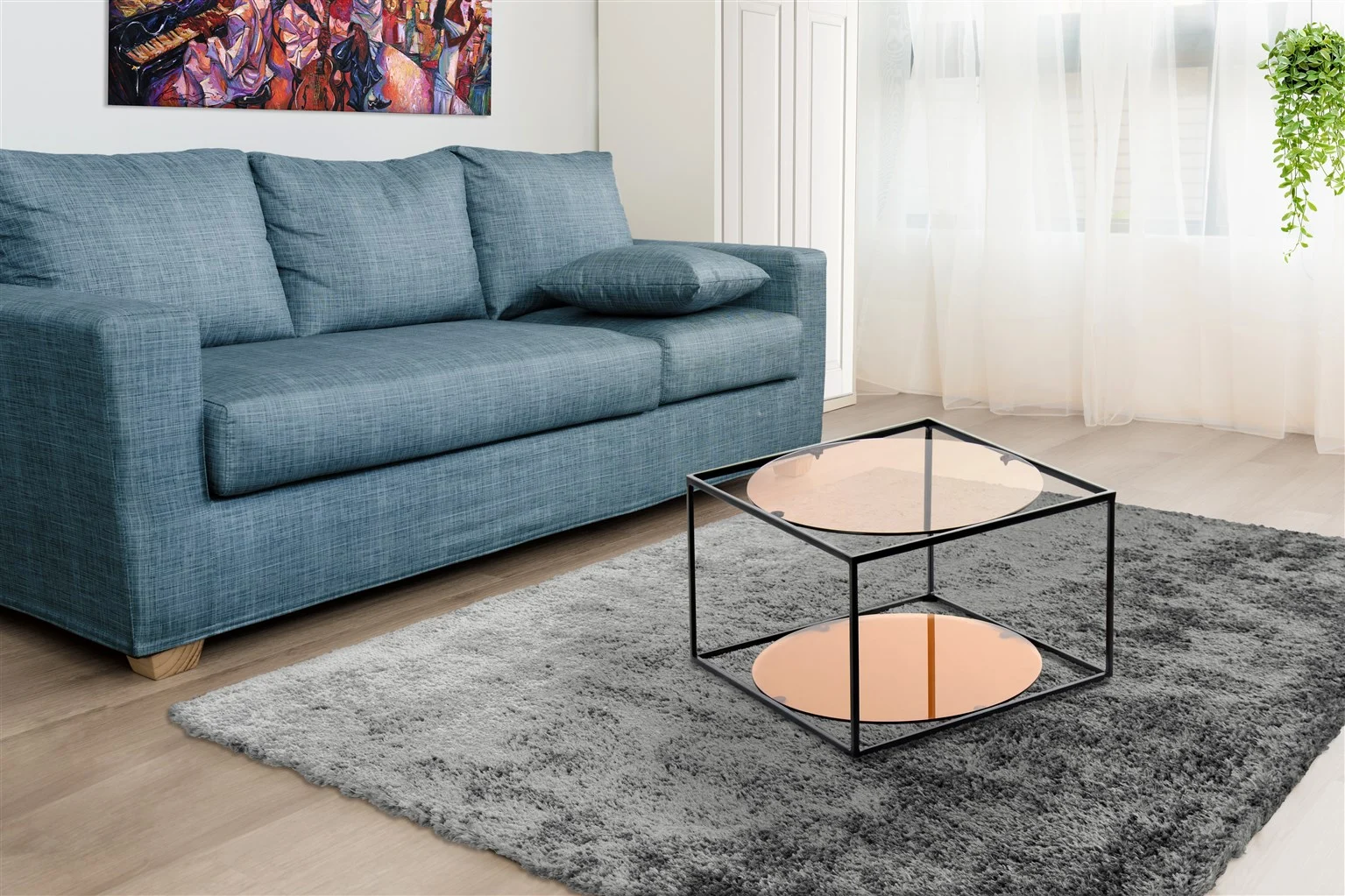 Een moderne woonkamer met een blauwe bank, grijs vloerkleed, de Bijzettafel Zwart Rond Metaal als zwarte ronde metalen salontafel, een kleurrijke muurschildering, transparante witte gordijnen die licht binnenlaten en een hangplant bij het raam.