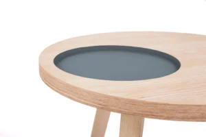 De Bijzettafel Grijs MDF is een ronde houten tafel met een lichte houten afwerking, met een verzonken cirkelvormig grijs blad in het tafelblad tegen een witte achtergrond.