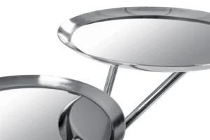 Close-up van twee ronde, glanzende Bijzettafel Zilver Rond Ijzer Design met opstaande randen, verbonden door gehoekte metalen stangen, tegen een witte achtergrond.