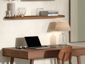 Zijaanzicht van een eiken bureau met laptop, lamp en stoel. Warme belichting, houten planken aan de muur. Minimalistisch interieur.