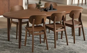 De SENTO TAFEL 210 EL21, een houten eettafel met afgeronde hoeken, wordt gecombineerd met zes bijpassende stoelen op een vloerkleed met patroon en gedecoreerd met een zwart dienblad, glaswerk en een kleine plant.