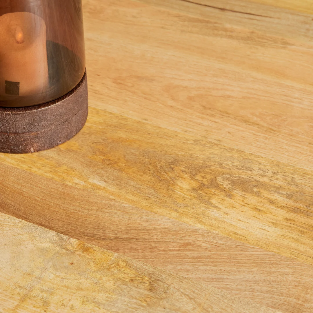 Een bruine kaars in een glazen houder met een houten onderstel staat op de Eettafel Denver, een ronde eettafel van mangohout van 120 cm.