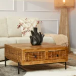Een moderne woonkamer met een lichte bank, Salontafel 80 x 80 CM Vierkant, zwarte sculpturale vaas met rode bessen, beige deken, staande lamp en een grijs vloerkleed op een houten vloer.
