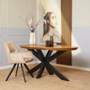 Een moderne eethoek met de Eettafel Brandy Ovaal 180 cm houten tafel met een zwart metalen onderstel, een beige gestoffeerde stoel, roze bloemen in een vaas, wandkunstwerk van een vrouw met een vogel, lichthouten vloeren en wanden met lambrisering.