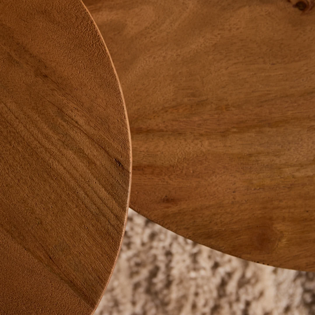 Bovenaanzicht van een houten salontafel design met warme tinten en een zichtbare houtnerf. Zachte belichting accentueert de ronde vorm.