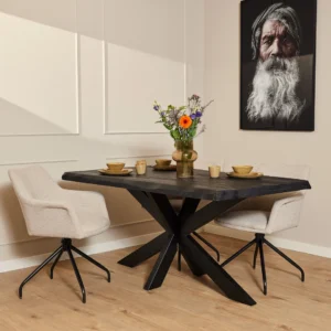 Een moderne eethoek is voorzien van de Boomstamtafel Boston Zwart (160 cm), twee beige stoelen met kussens, bruin servies, een vaas met kleurrijke bloemen en een portret van een oudere man met een grijze baard aan de muur.