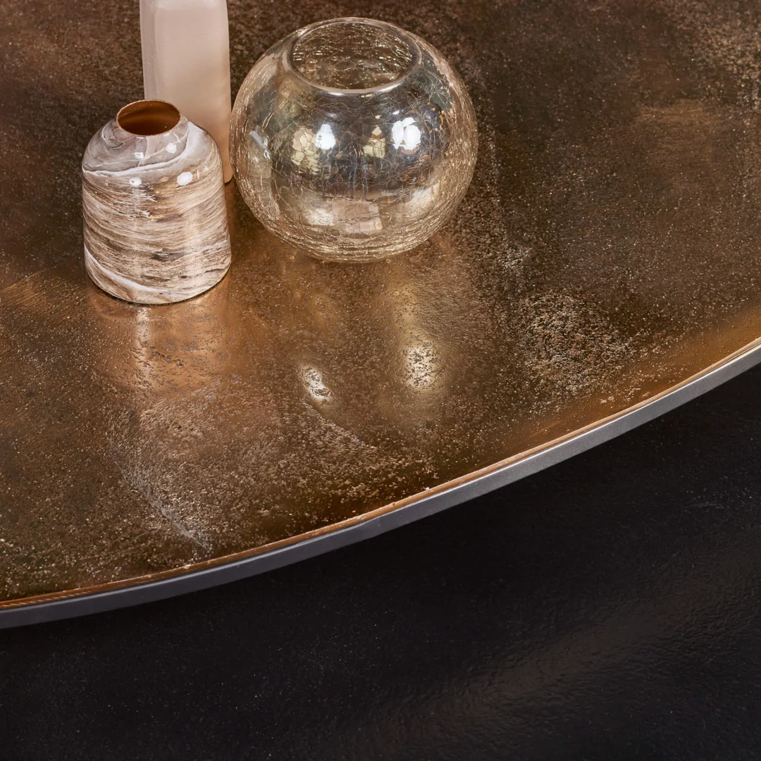 Drie decoratieve vazen - één van glas en twee van keramiek - staan op de Salontafel 70 CM Nesting Set, een ronde bronskleurige metalen tafel met een gestructureerd oppervlak tegen een donkere, gladde achtergrond.