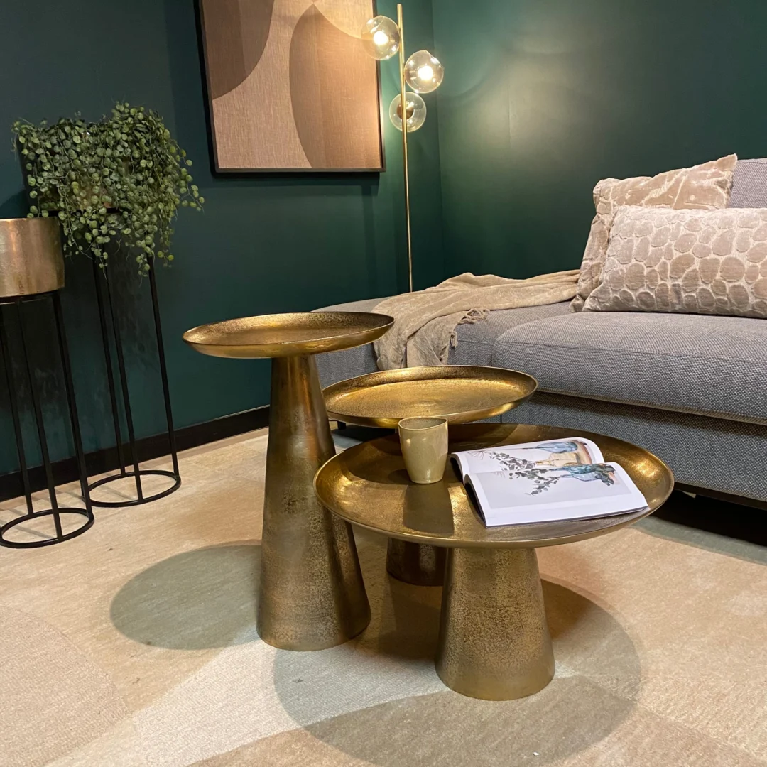 De Salontafel 50 x 50 CM Vierkant, gestyled met een kopje en een open tijdschrift, staat in een moderne woonkamer met een grijze bank, beige kussens, groene muren, een vloerplant en een globe vloerlamp op de achtergrond.