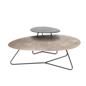 De Salontafel Rond Opbergvak set bestaat uit twee ronde, minimalistische salontafels met dunne zwarte metalen poten: een met een gestructureerd koperen blad en de andere - iets hoger geplaatst - met een glad zwart blad.