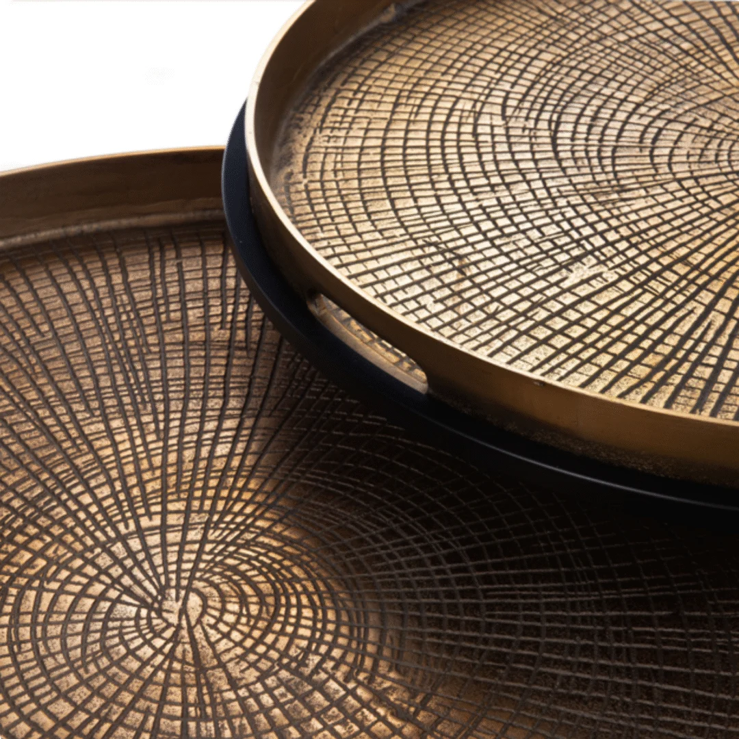 Detailopname van goudkleurige, ronde dienbladen met een geometrisch patroon. Mooie decoratie voor een Scandinavische salontafel.