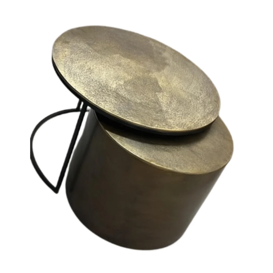 Schuine weergave van een gouden salontafel met een rond blad en een cilindrische basis. Zwart metalen accenten. Neutrale achtergrond.