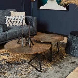 Een moderne woonkamer met een Salontafel 60 x 60 CM Vierkant salontafel, kandelaars, een grijze gestructureerde bank met gedessineerde kussens, een goud en grijs vloerkleed en muurkunst met een deel van iemands gezicht en nek.